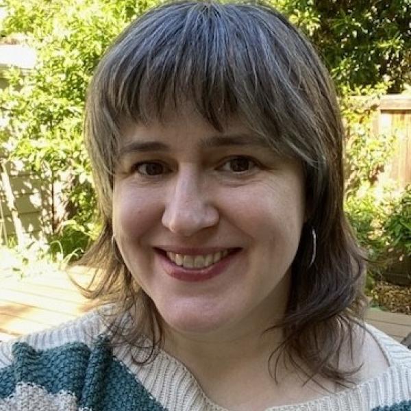 Headshot of woman with shoulder length hair and straight bangs smiling