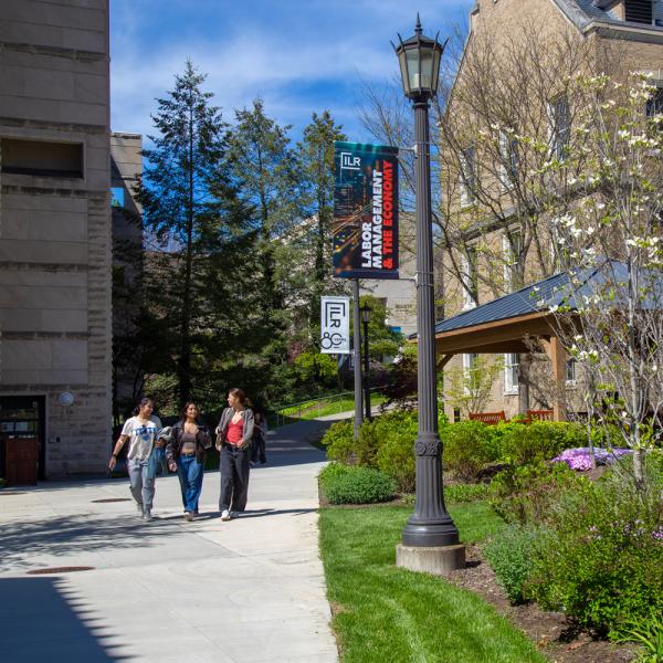 three students walking through ILR School courtyard