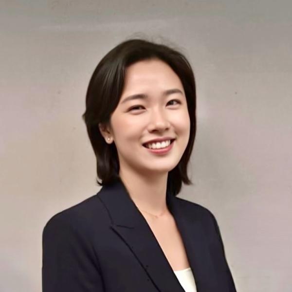 Professional headshot of a smiling woman wearing a dark blazer against a neutral background.