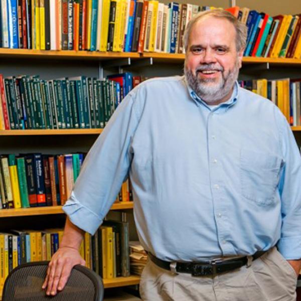 Marty Wells standing in front of a bookcase.