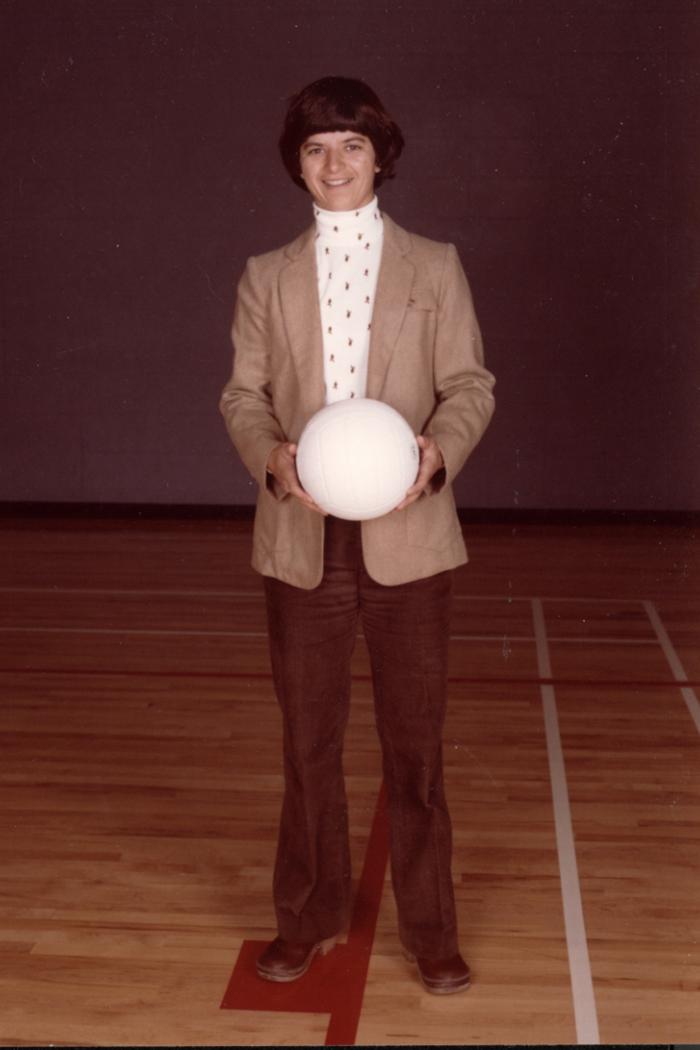 Andrea Dutcher standing on a court holding a volleyball.