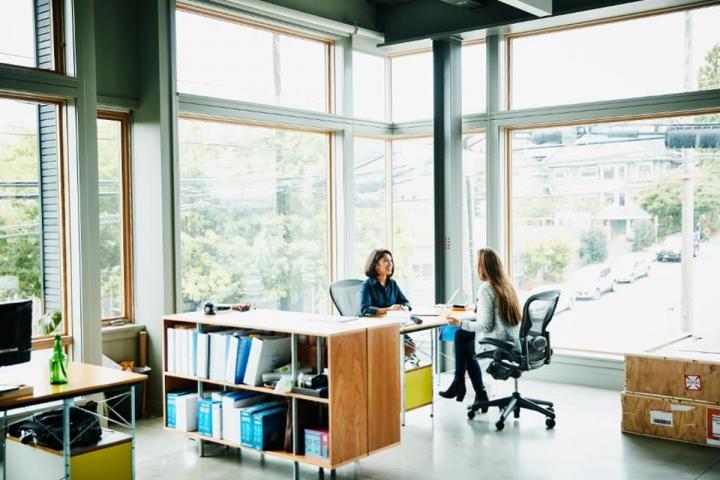 Two women talking to each other, seated at a table