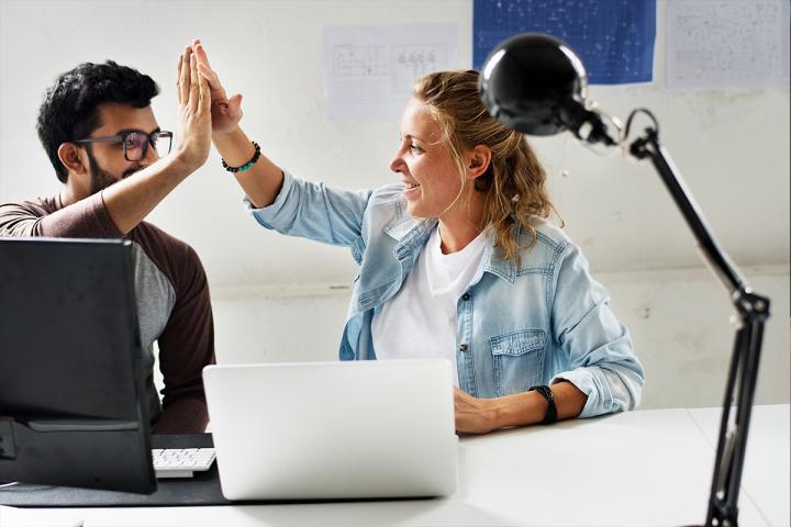 Two people working next to each other and high-fiving each other