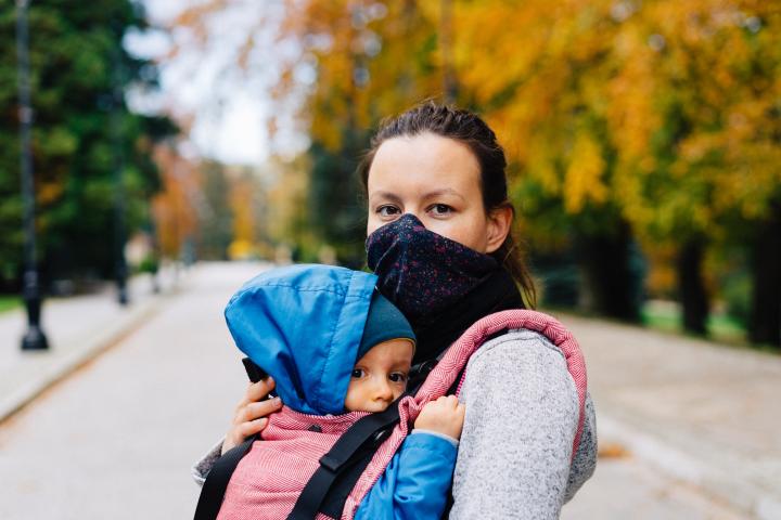 Photo of masked woman carrying a child by Marcin Jozwiak on Unsplash