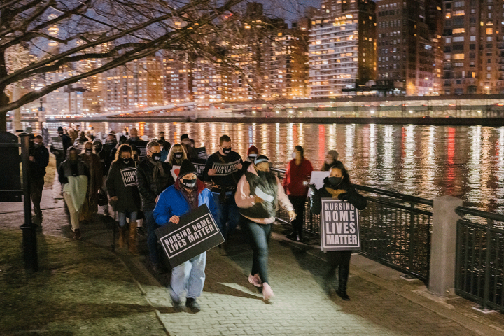 Group of people in NYC holding a night vigil holding signs that say, "Nursing Home Lives Matter".