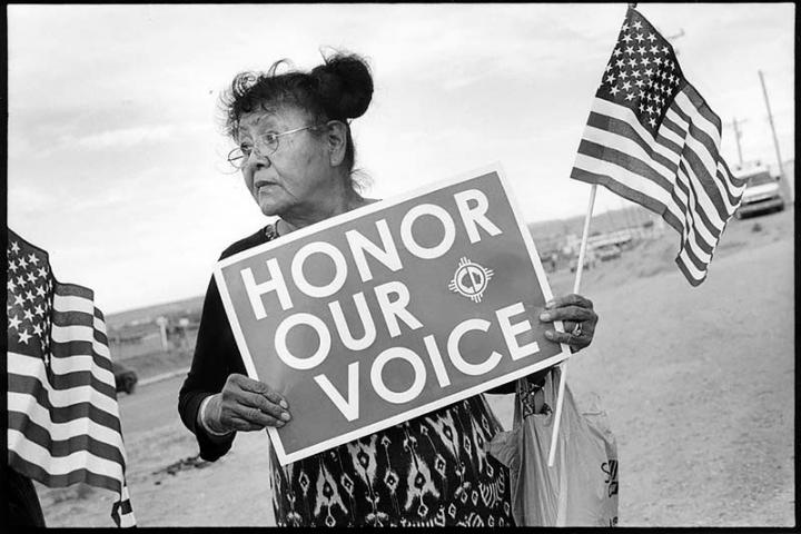 Woman holds a sign reading "Honor Our Voice"
