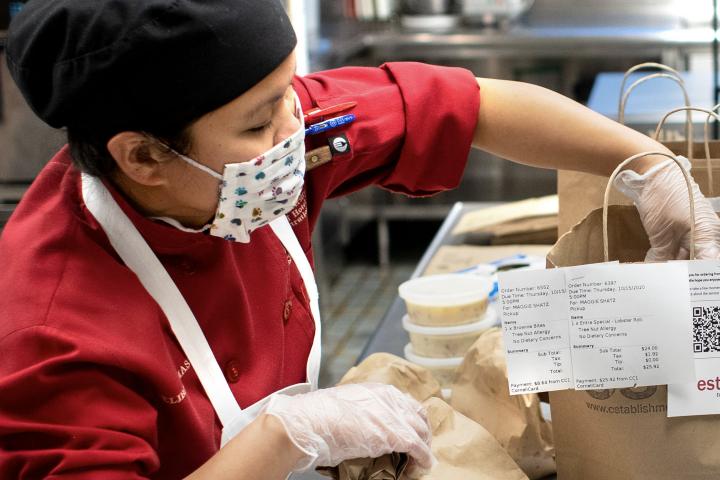 A masked food worker packages food