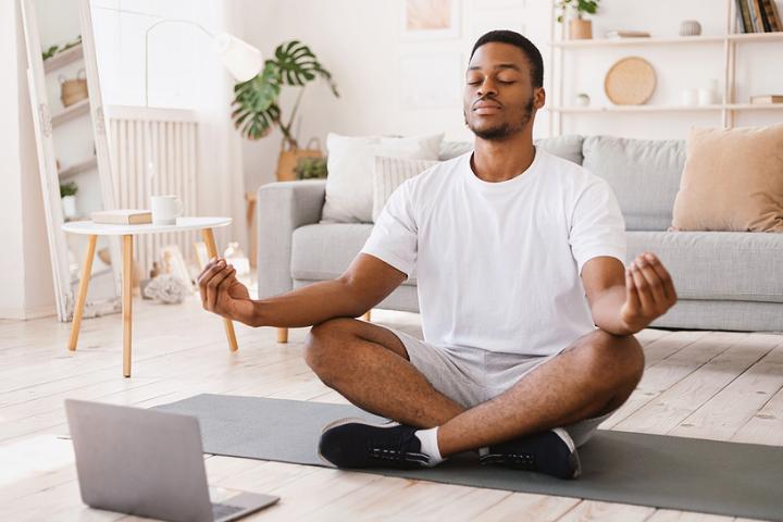 A young man practices yoga in his living room.