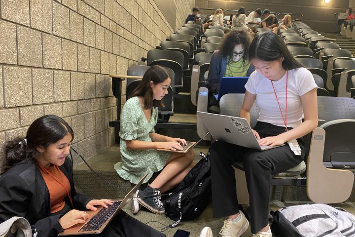 students sit working on their laptops