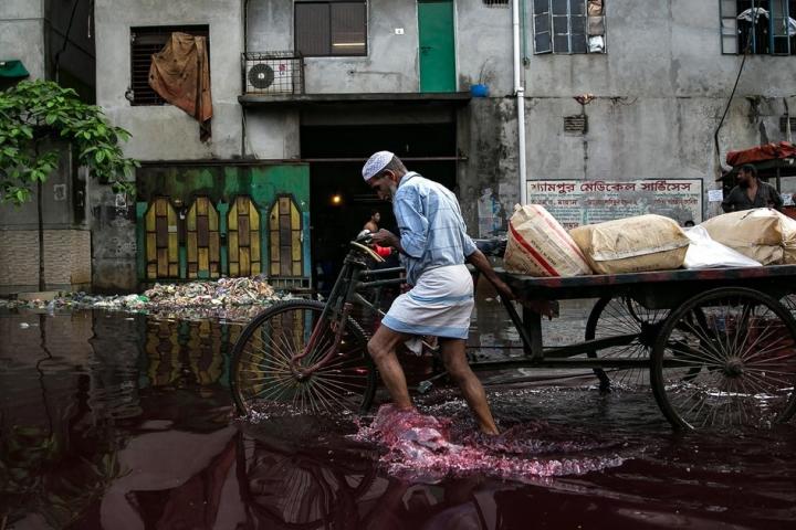 A man walks through rain and dye outside a dyeing factory in Bangladesh. (Getty)