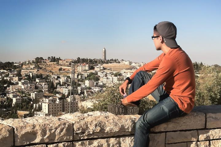 Person sitting on a wall overlooking a city