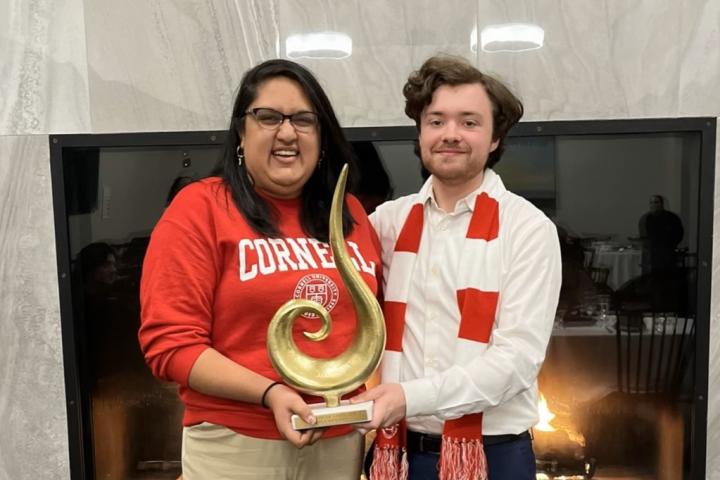Two students in Cornell apparel hold the winning trophy