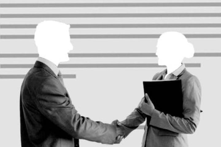 Two faceless individuals in suits shake hands.