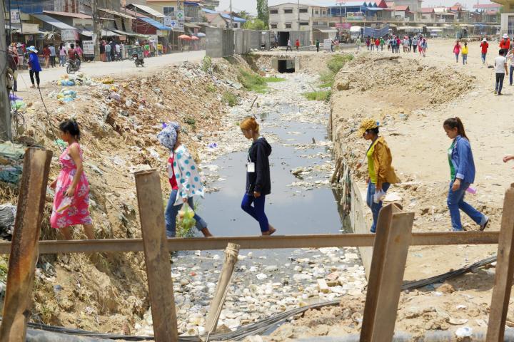 Workers walking across a precarious bridge over scant water