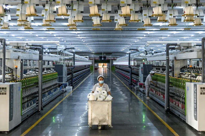 Person pushing a cart full of paper product through a factory. 