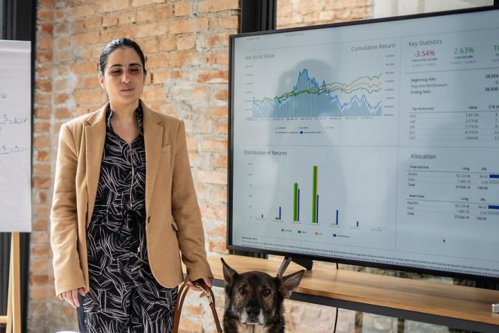 An officeworker gives a presentation and is accompanied by a service dog