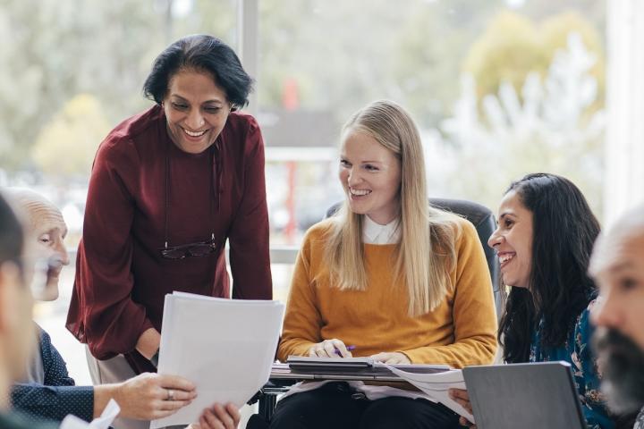 A group of people at an in-person training are reviewing a printed document.