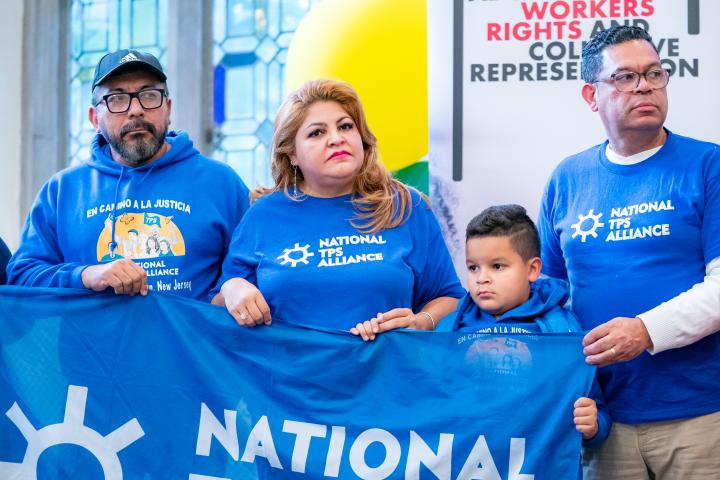 Four family members standing and holding a National TPS Alliance Flag