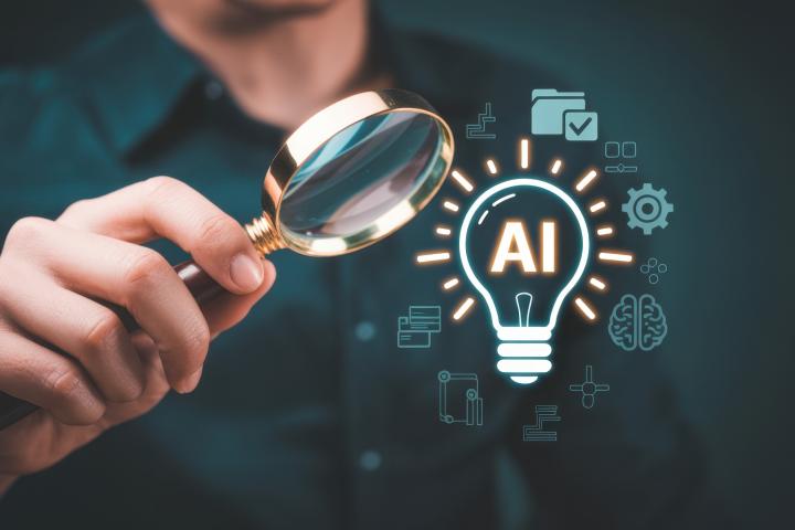 A person uses a magnifying glass to examine a glowing AI lightbulb surrounded by digital business and technology icons.
