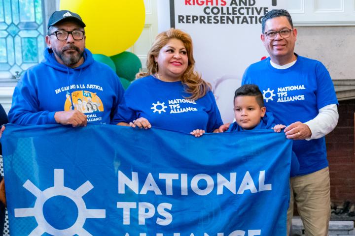 Individuals from the National TPS Alliance standing with a banner. 