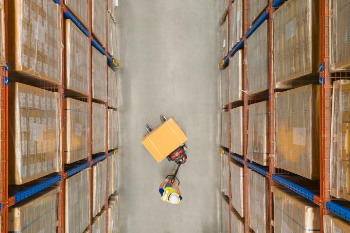 overhead shot of warehouse worker pushing boxes with surrounding shelves of packages