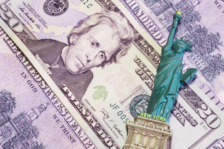Figurine of Statue of Liberty with money bills in background