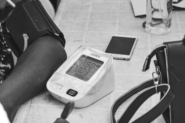 An arm rests next to a blood pressure monitor and a smartphone.