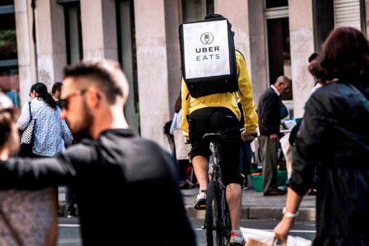Man riding a bicycle with an Uber Eats bag
