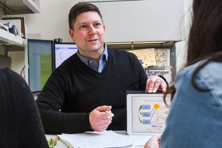 Associate Professor Adam Seth Litwin speaks with students in his office. 
