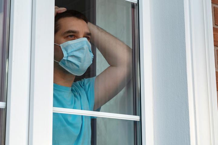 Man in a medical mask near the window.