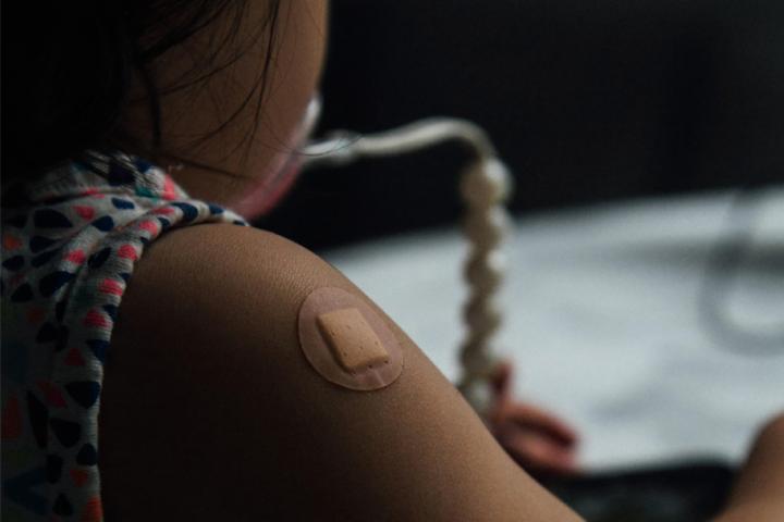 An image of a girl's arm with a bandaid following a vaccination. 