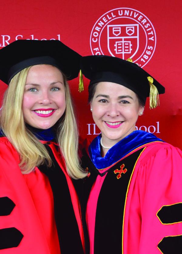 Two people wearing cornell doctoral regalia at graduation
