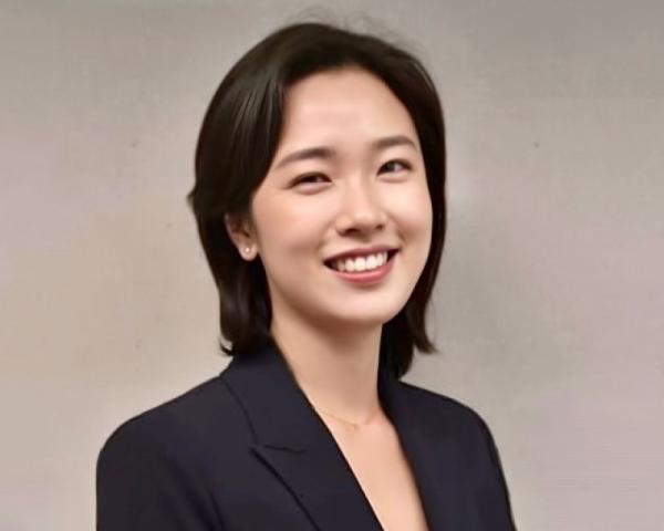 Professional headshot of a smiling woman wearing a dark blazer against a neutral background.
