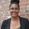 Headshot of Tiffany Gibson in a black blazer behind a brick wall.