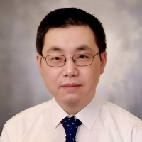 Professor Sheng Lu sits, wearing a white shirt and a dark tie. He wears glasses and has short dark hair.