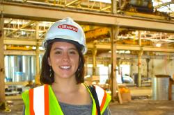 Emily Bramhall wears a hard hat and reflective vest and holds floor plans as she visits a Buffalo construction site.