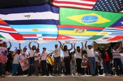 Protestors stand under a large canopy of flags of the world sewn together