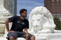 Jean Rios sits in front of a marble lion statue