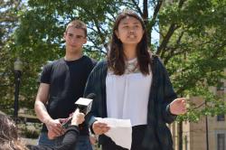 Wendy Lau stands with notes in hand and an unidentified man behind her in support as a reporter holds a mike up to her.
