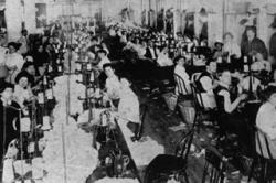 Rows of women seated at sewing machines in a room of the Triangle Shirtwaist Factory before the fire