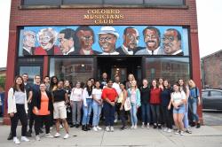 Buffalo students and staff stand in front of the Colored Musicians Club in Buffalo, NY under a mural of famous African-American musicians.